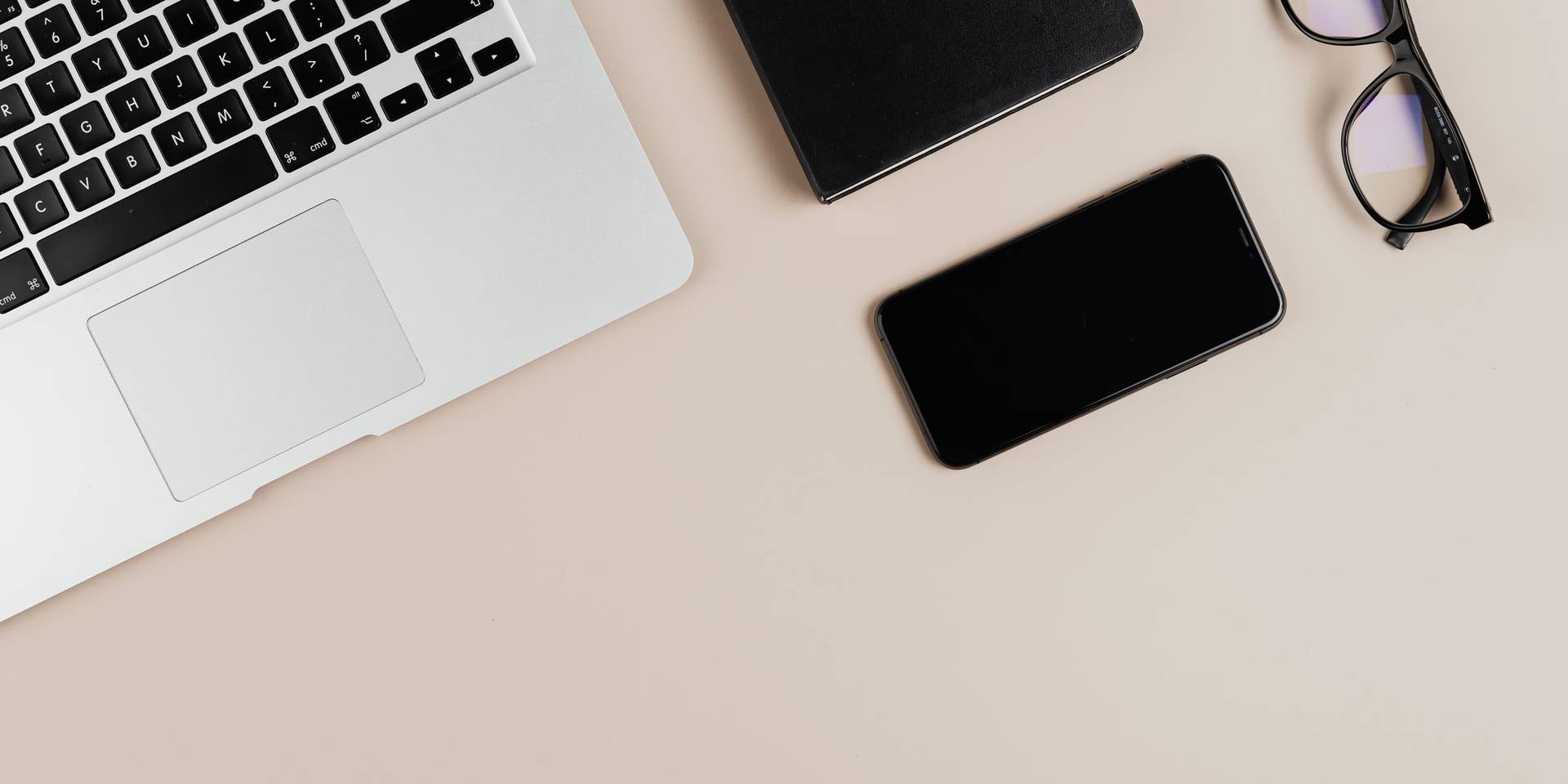 Telefon, laptop i okulary na beżowym blacie
